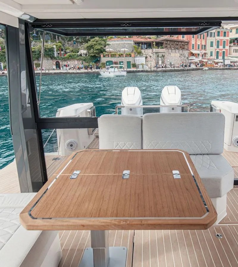Teak cockpit table and white seating of the Saxdor 400 GTO, harbor houses behind