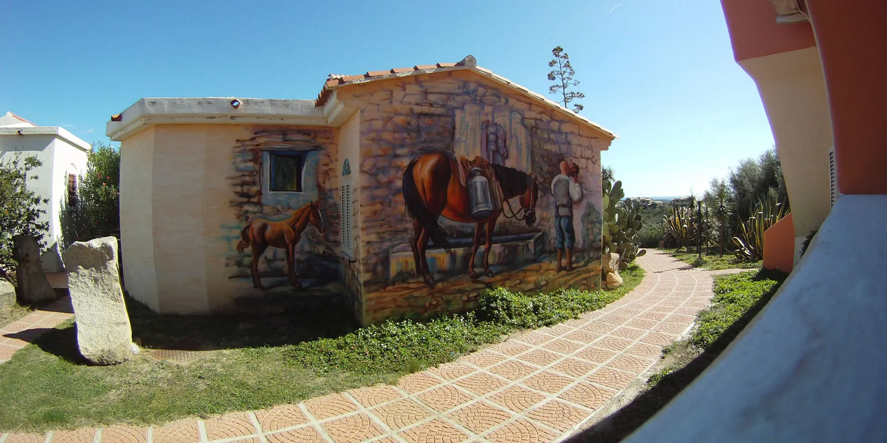 Mural of a horse, a foal and a farmer painted on a stone house inside the village