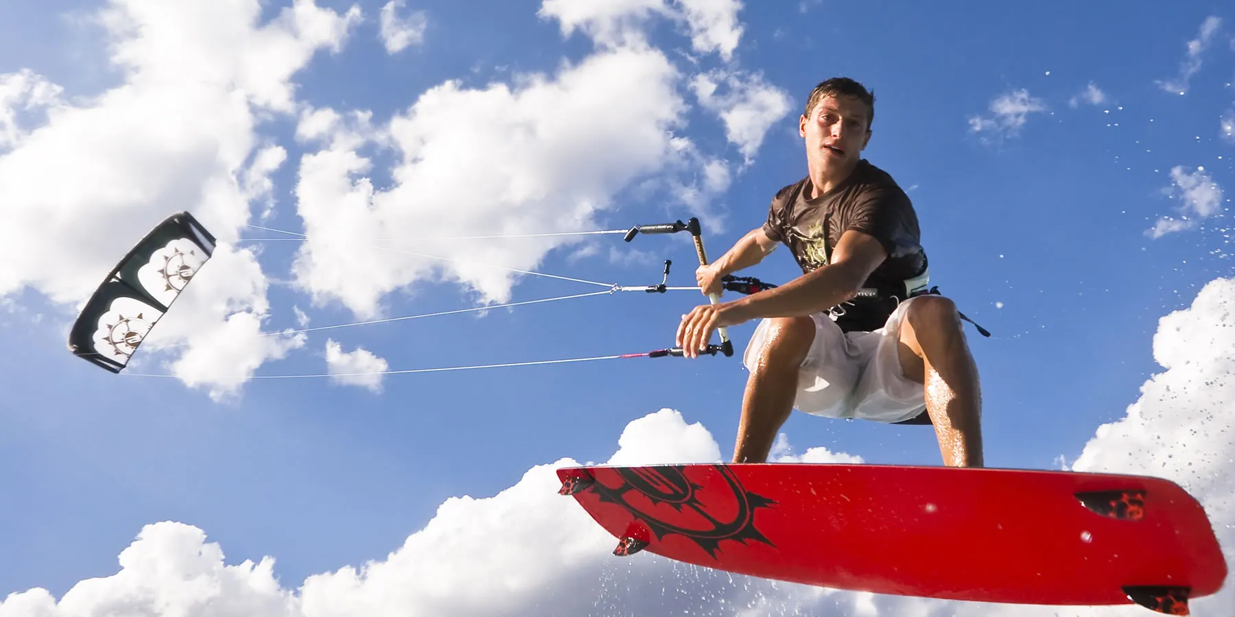 Kitesurfer jumping high against a blue summer sky
