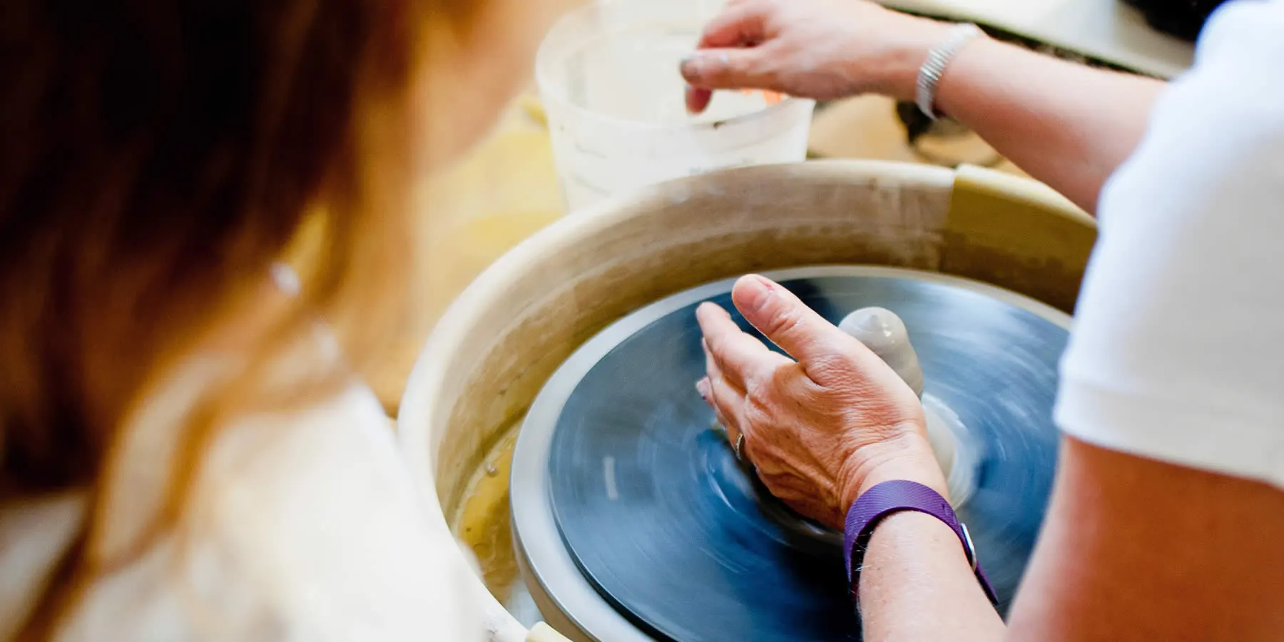 Hands shaping clay on a spinning potter's wheel