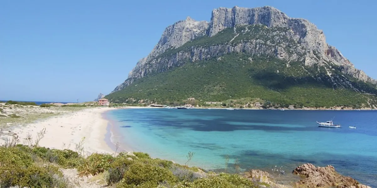 The long white beach below Tavolara island, shallow turquoise water fading into deep blue