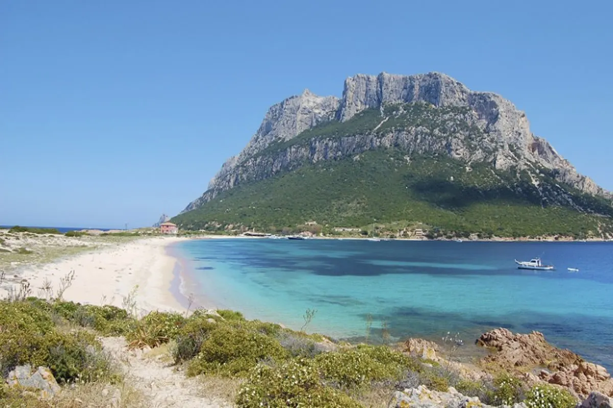 Tavolara island rising over a white sand beach and turquoise water