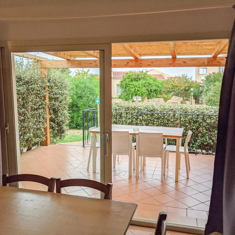 Glass doors of a three-room apartment opening onto a pergola patio and garden