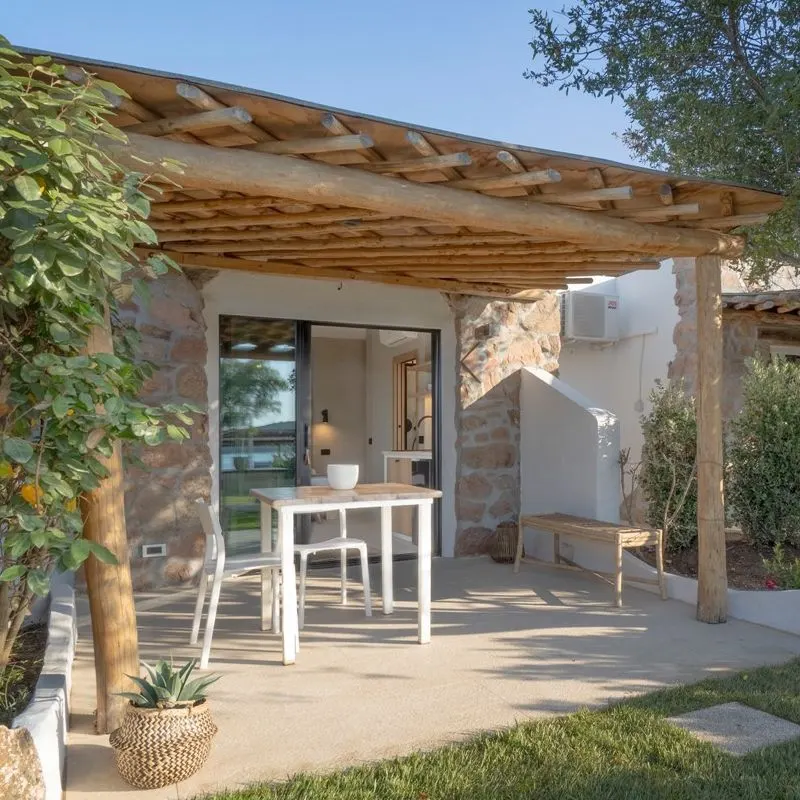 Stone studio cottage with a juniper pergola shading its terrace table
