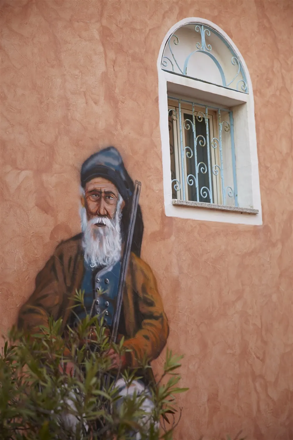 Mural of a Sardinian shepherd on a terracotta wall of the village